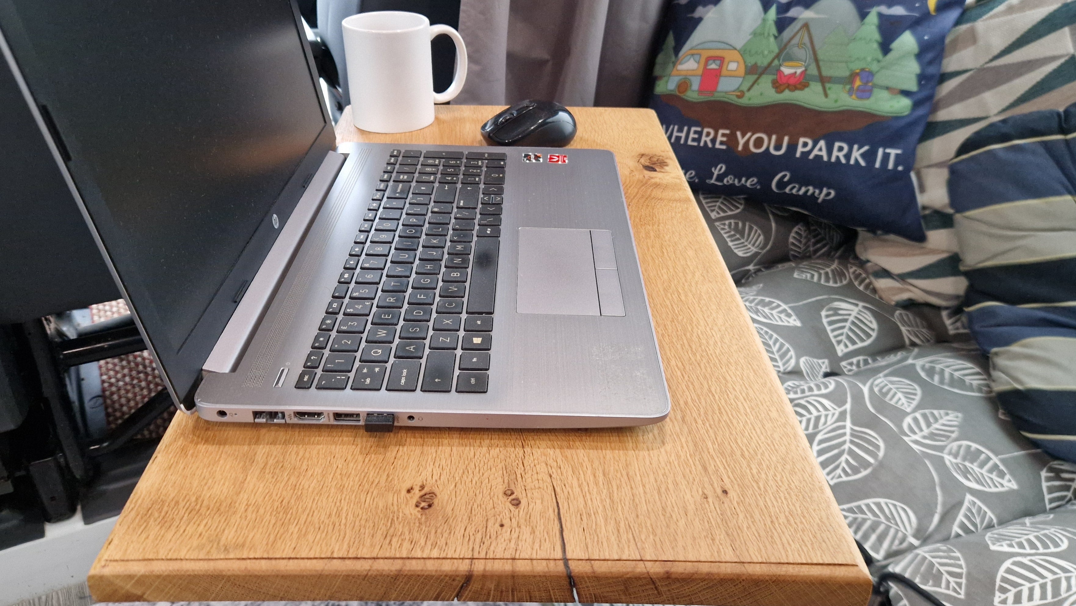 Solid oak campervan table set up with laptop, mouse and coffee mug showing practical workspace inside a van conversion.